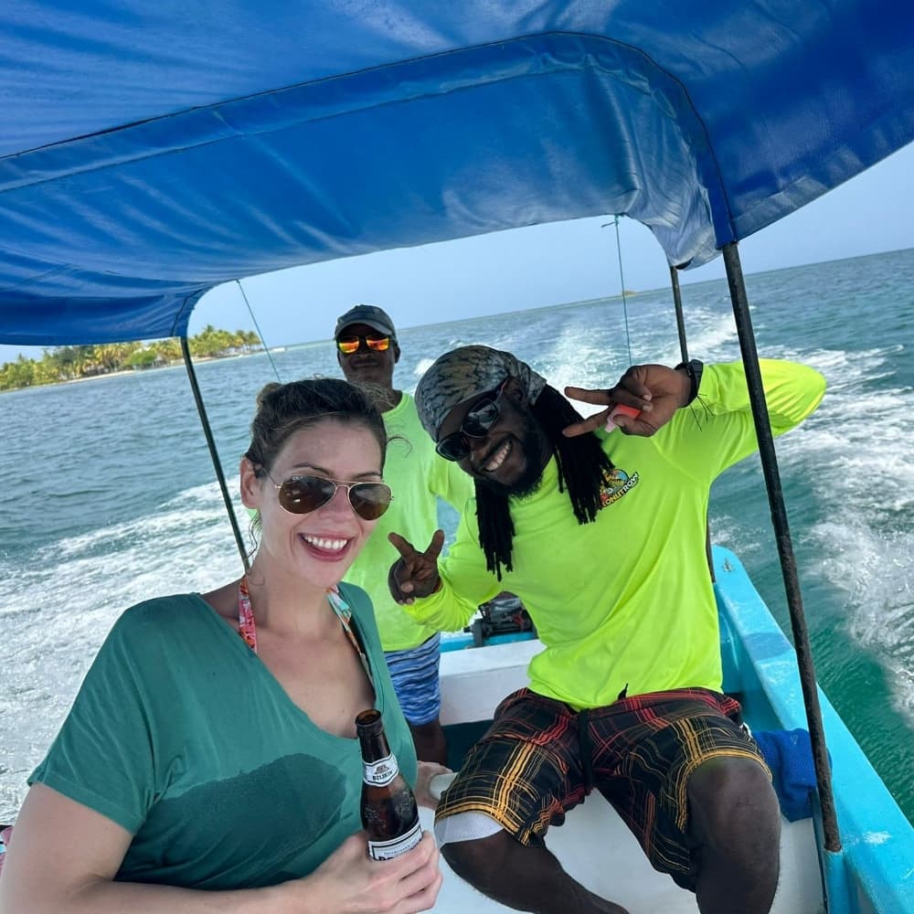 Three people enjoy a boat ride on a sunny day, with one woman holding a drink and the others posing for the camera.