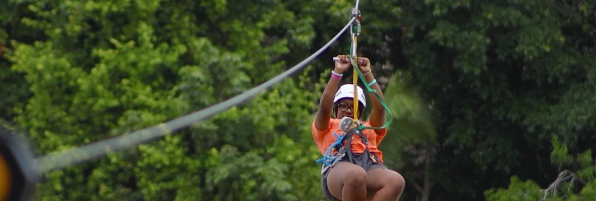 A person confidently zips across a zip line surrounded by lush greenery.
