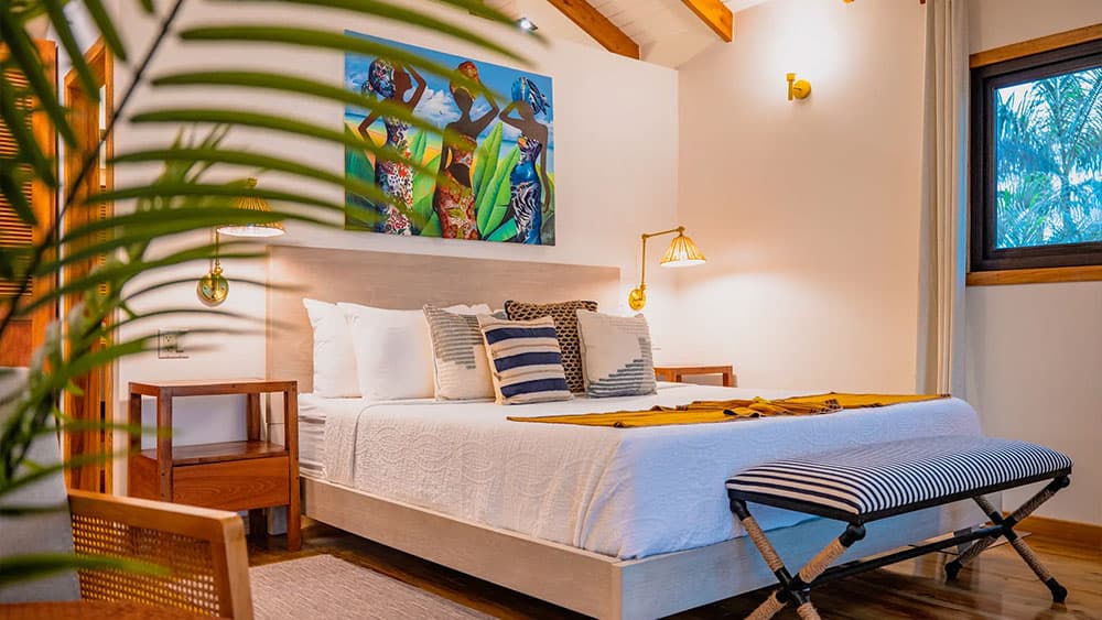 A cozy bedroom featuring a double bed, colorful artwork, and warm wooden accents.