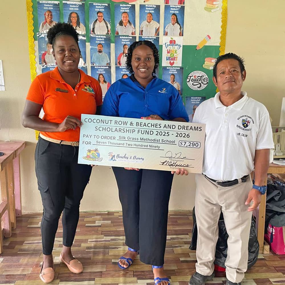 Three individuals hold a large scholarship check for the Coconut Row & Beaches and Dreams Scholarship Fund in a classroom setting.