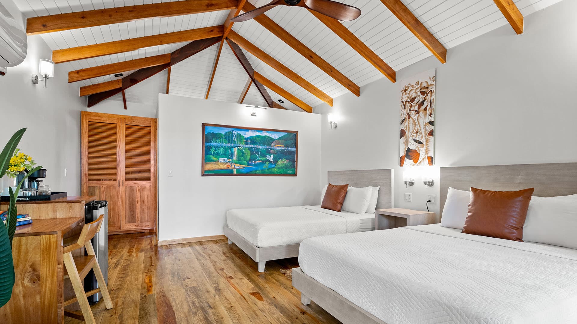 A cozy hotel room featuring two beds, wooden accents, and artwork on the walls.