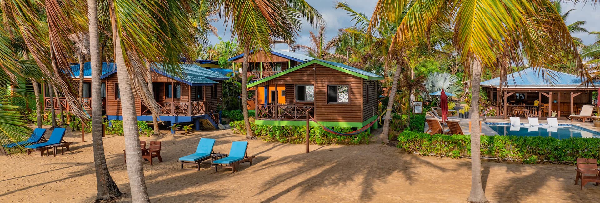 Tropical beachside bungalows surrounded by palm trees and lounge chairs.