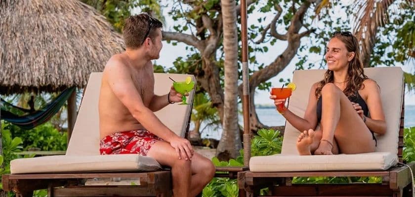 A couple relaxing while enjoying tropical drinks by the saltwater pool at Coconut Row.