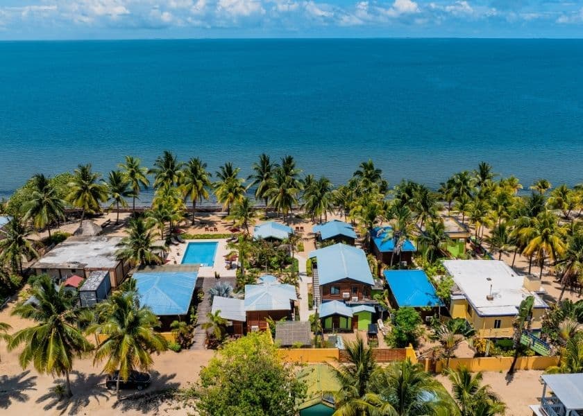 Aerial view of Coconut Rows beachfront cabanas, pool, palm trees, and the Caribbean Sea in Hopkins, Belize.