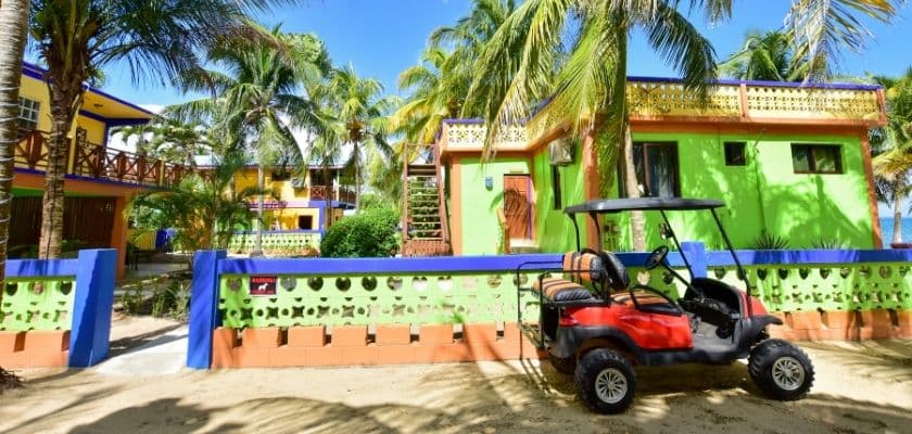 Golf cart parked outside Coconut Rows colorful beachfront accommodations in Hopkins, Belize.